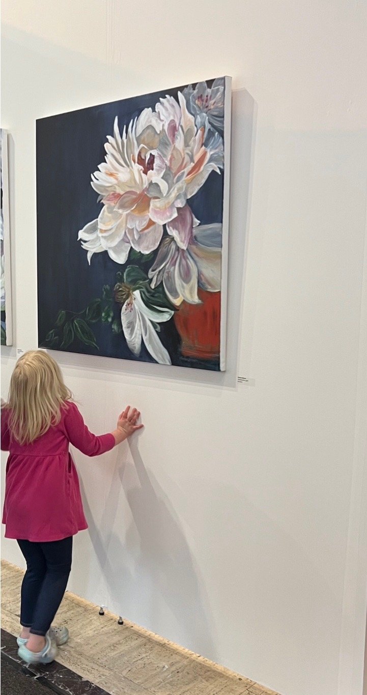 A young visitor admiring a peony painting at a gallery show