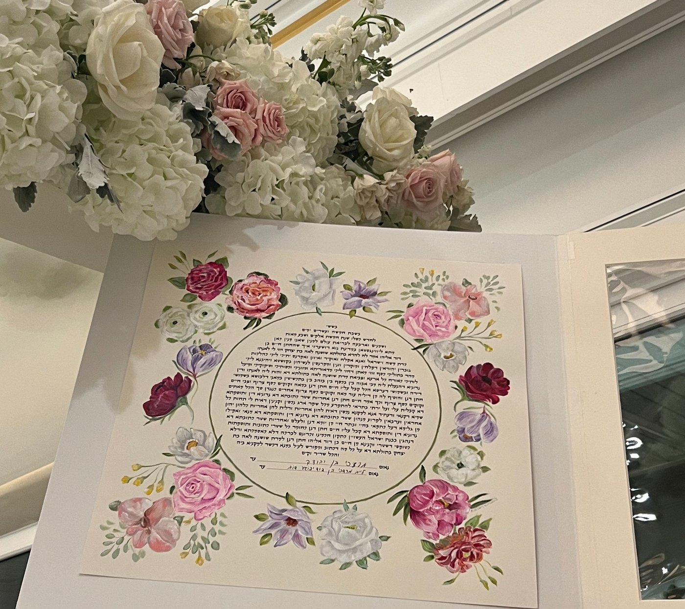 Floral ketubah displayed beside a wedding bouquet