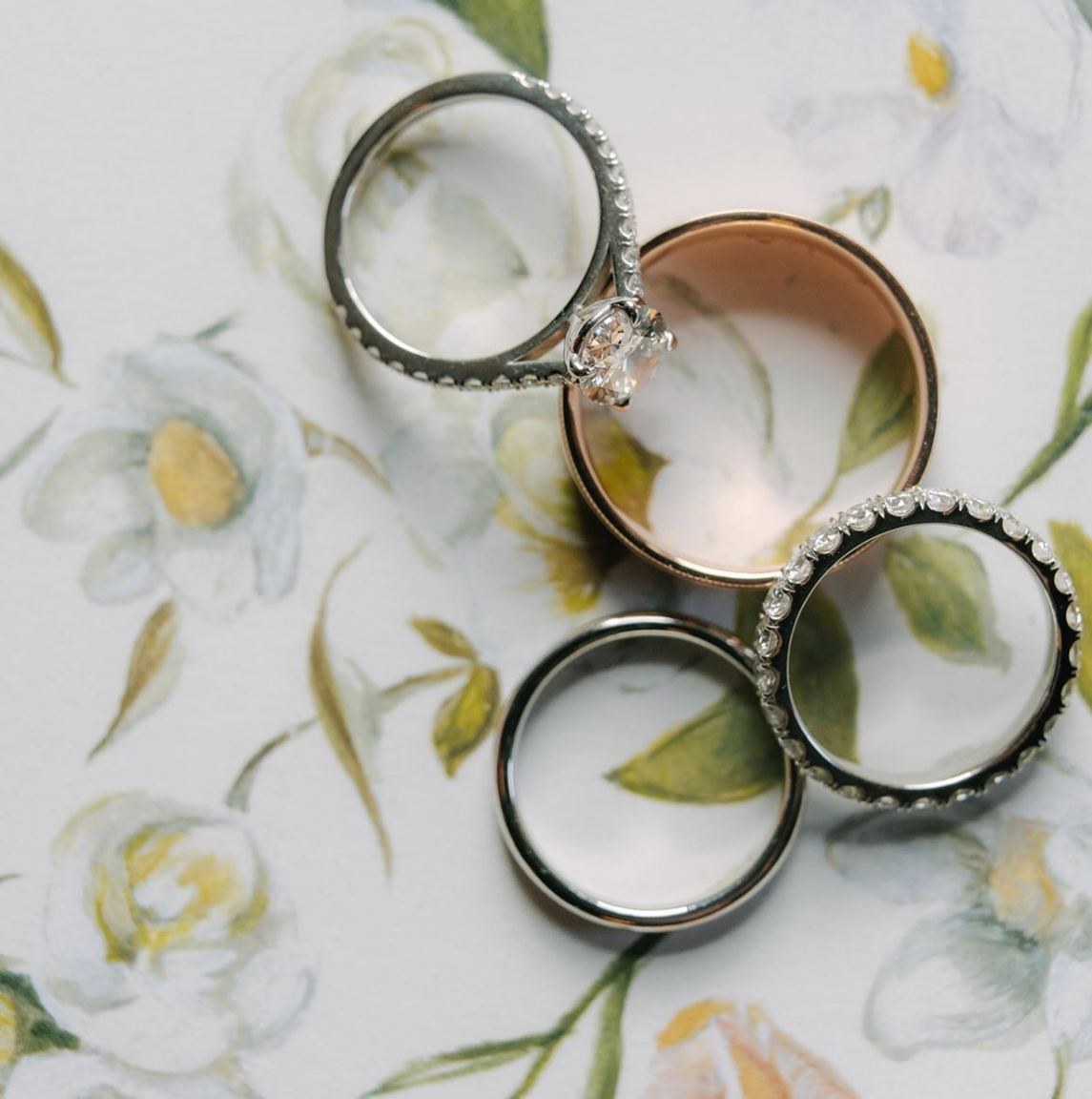 Wedding rings resting on a hand-painted floral design